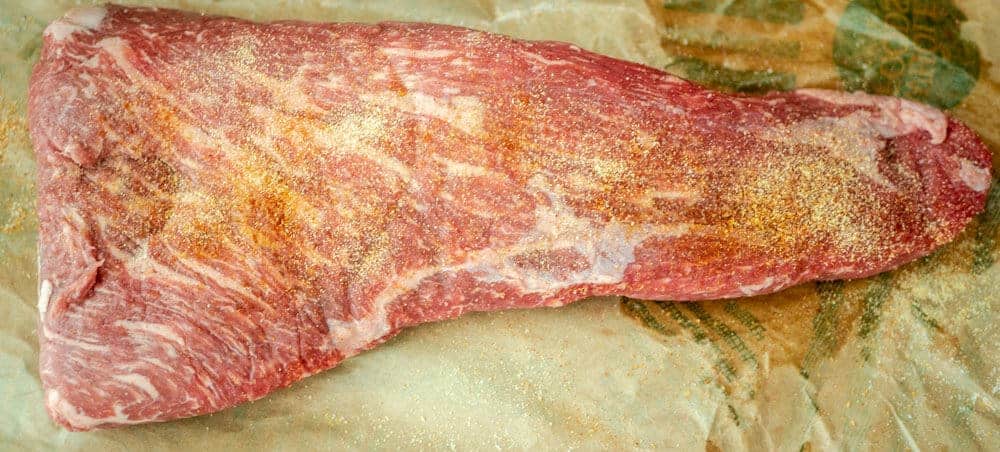 Seasoned raw tri tip roast ready for cooking.