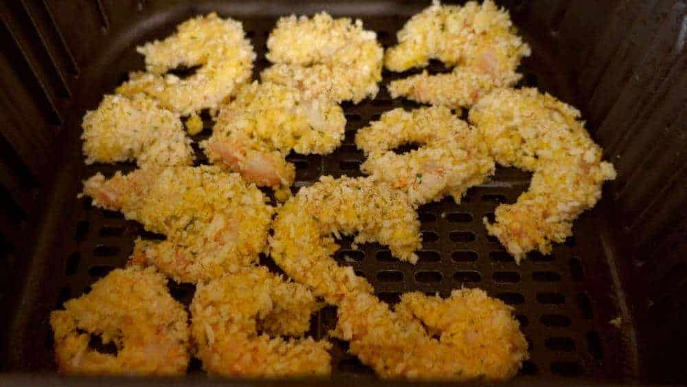 Breaded shrimp in air fryer basket ready to be cooked
