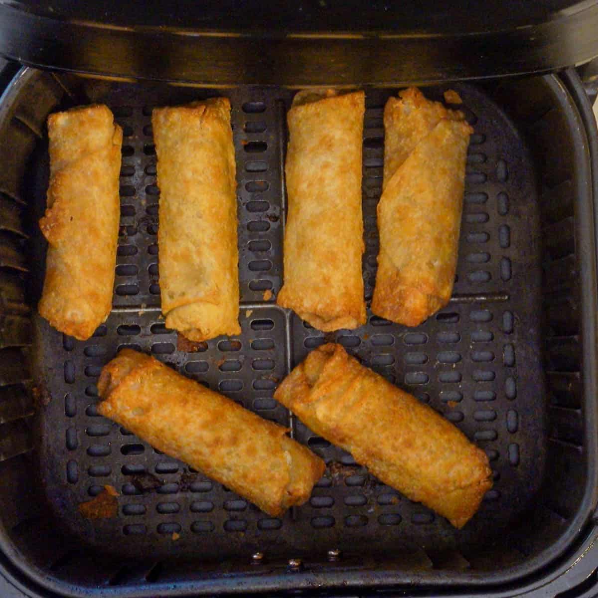 eggrolls cooking in air fryer basket