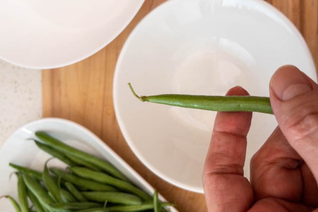 Showing bean end to be snapped off before cooking