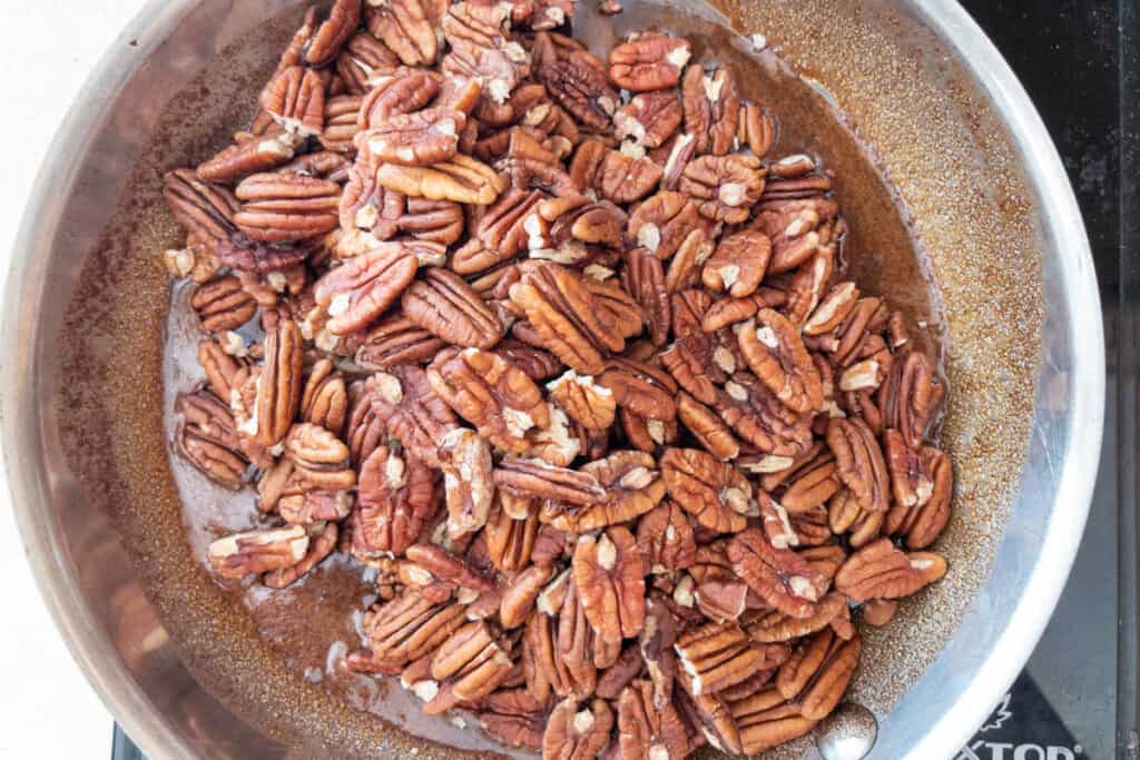 coating pecans in syrup mixture in pan