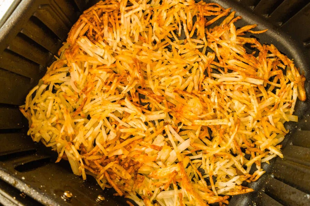 Golden brown crispy hash browns in the air fryer basket