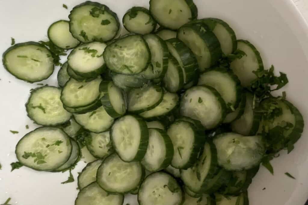 Cucumber salad final step adding cilantro vinegar salt and sugar.