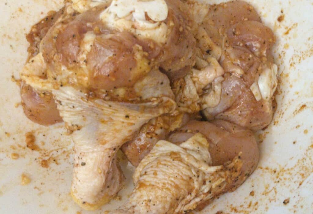 preparing black pepper air fryer chicken legs in a bowl with oil and spices