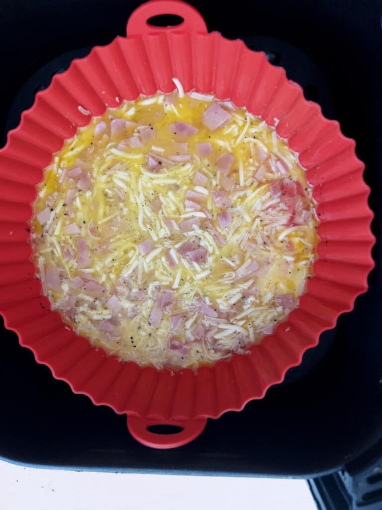 Air fryer ham and cheese omelette in air fryer basket ready to be cooked