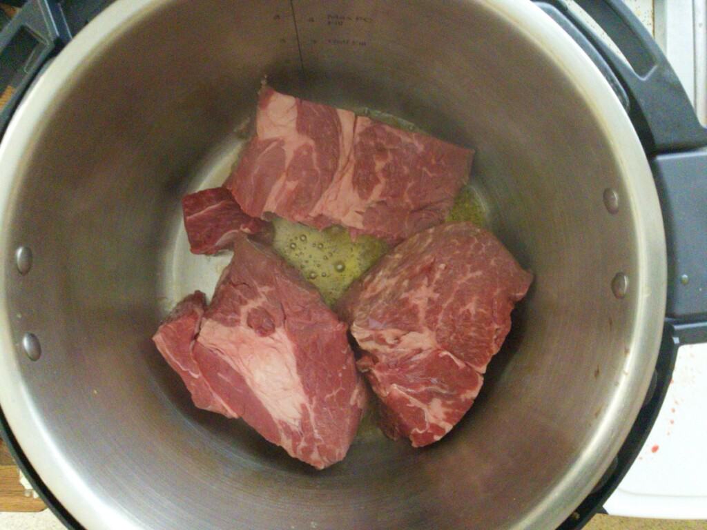 Pot roast in chunks being seared in instant pot for Mississippi pot roast. Step 2