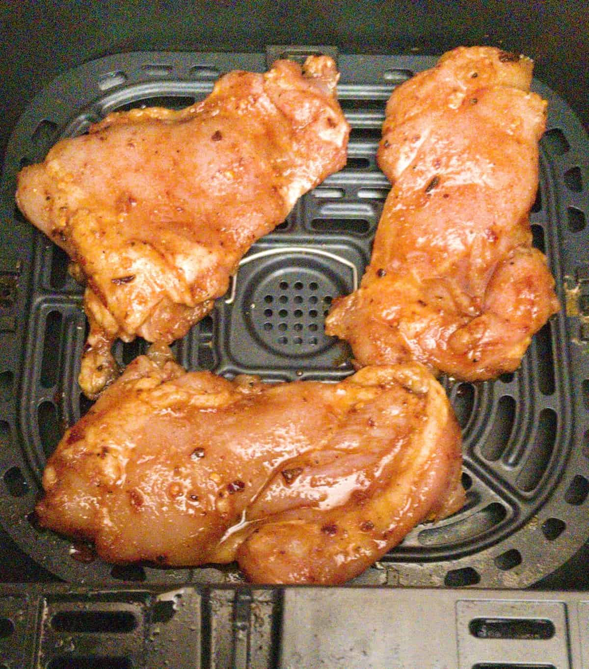 marinated boneless chicken thighs in air fryer basket ready to cook