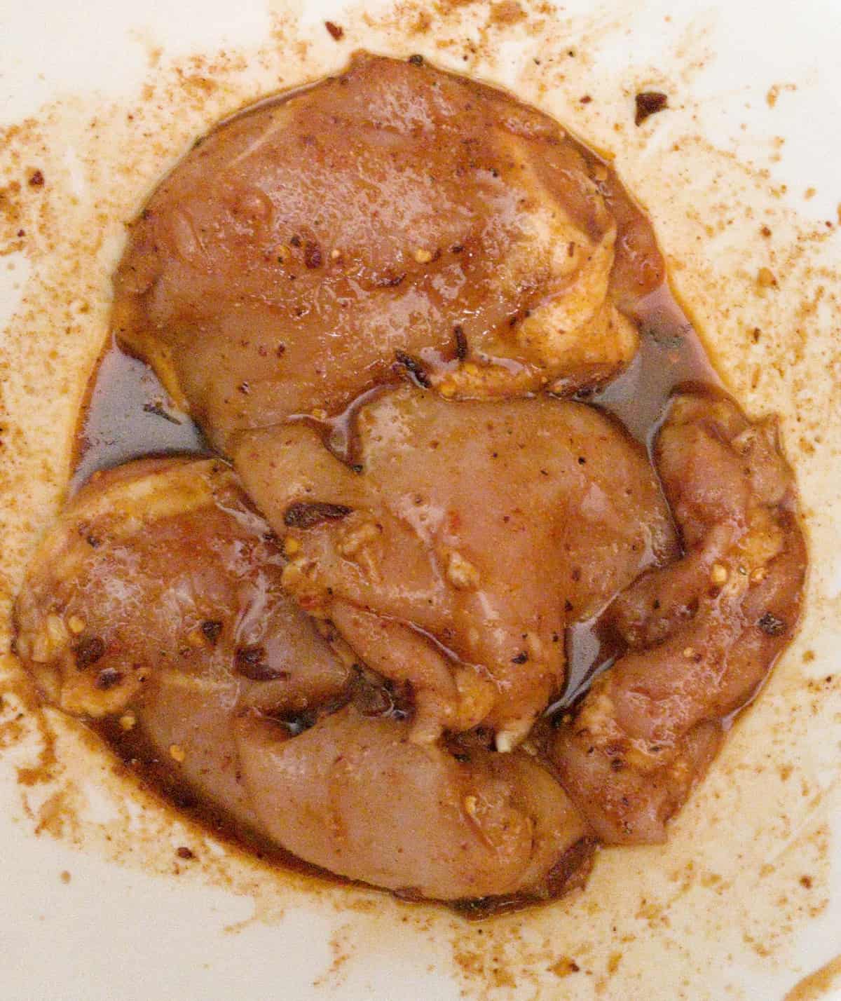 air fryer boneless chicken thighs in bowl with spices and marinade