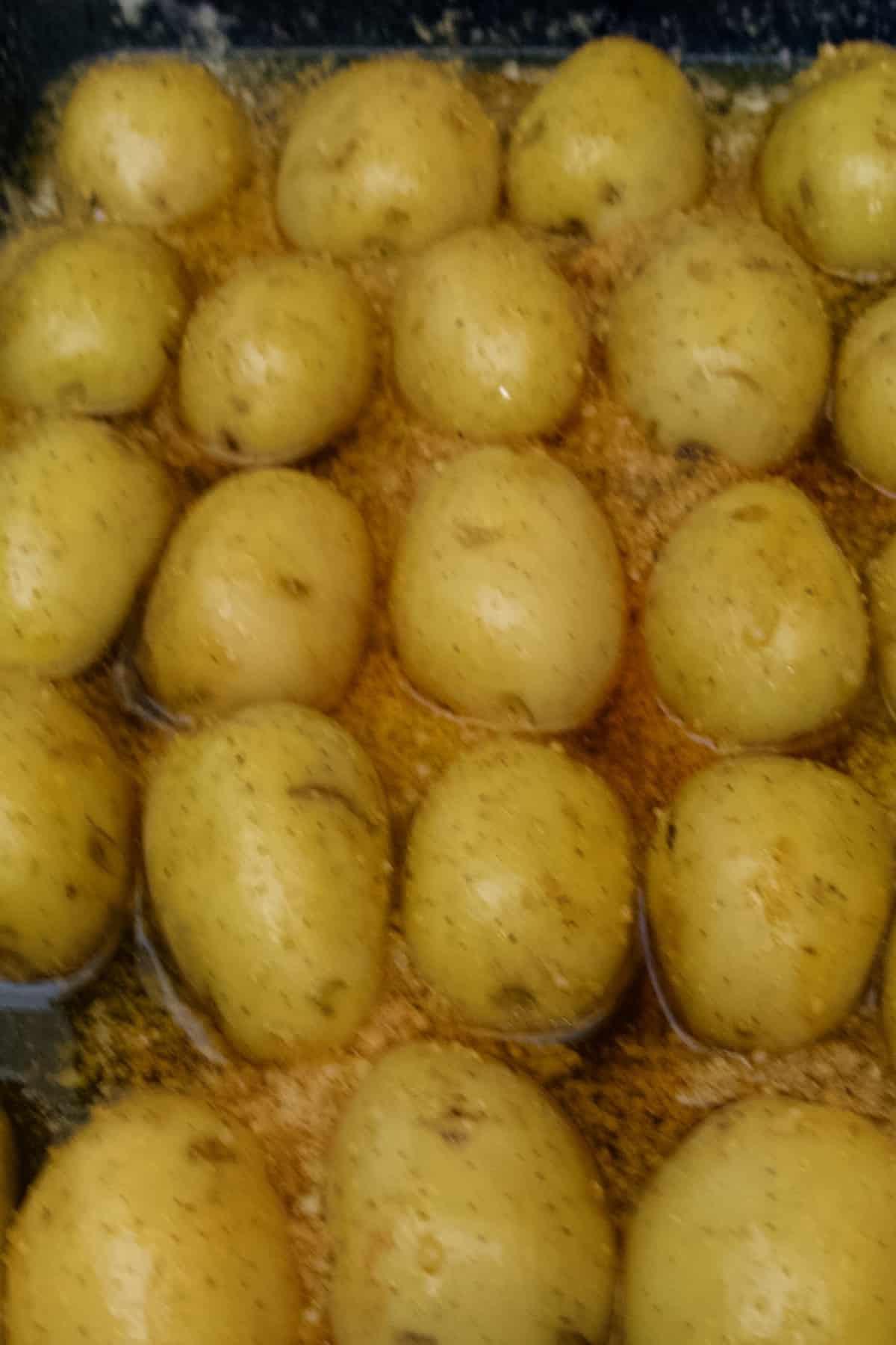 parmesan roasted potatoes cut side down in baking dish in butter and spices