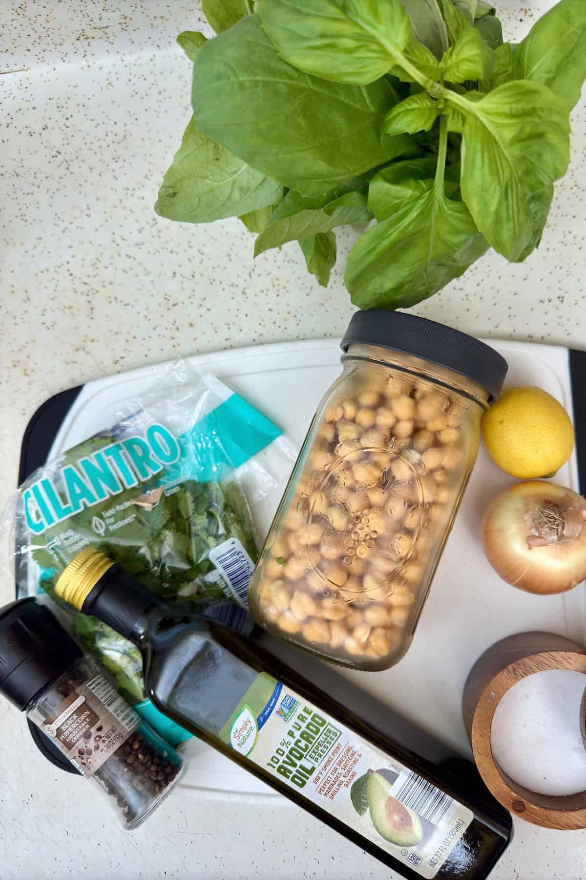 Soaked chickpeas and fresh ingredients for making falafel, including lemon, onion, herbs, and oil.
