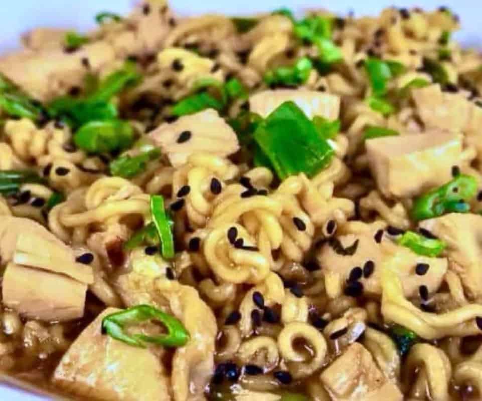 Bowl of homemade chicken ramen noodles with soy-garlic sauce, green onions, and sesame seeds.