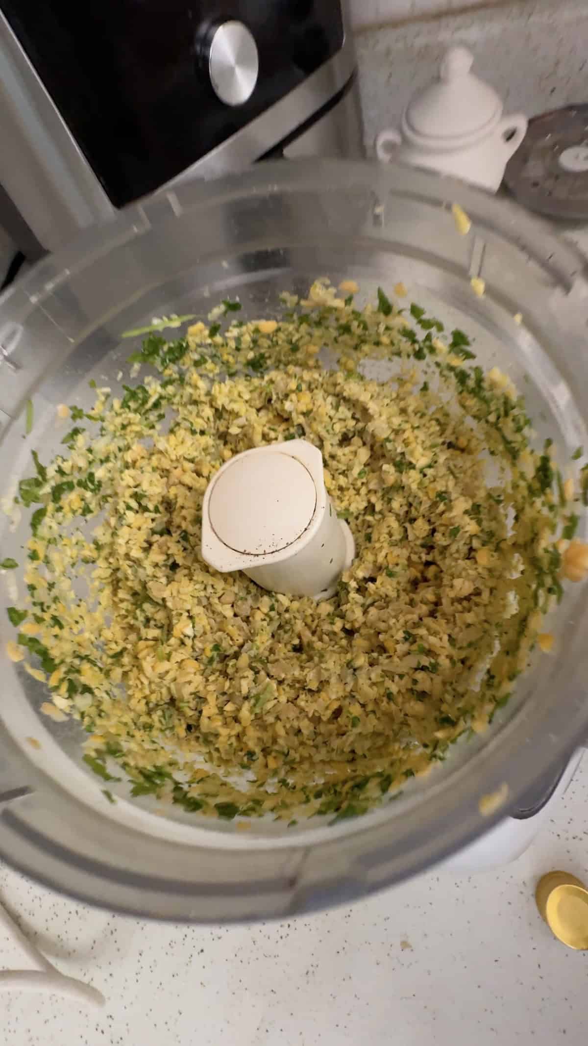 Blending chickpeas, fresh herbs, and seasonings in a food processor to make falafel.