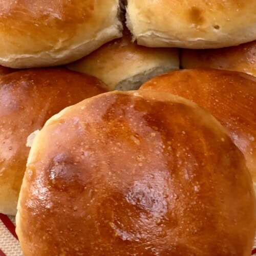 Homemade sandwich rolls stacked on a baking mat