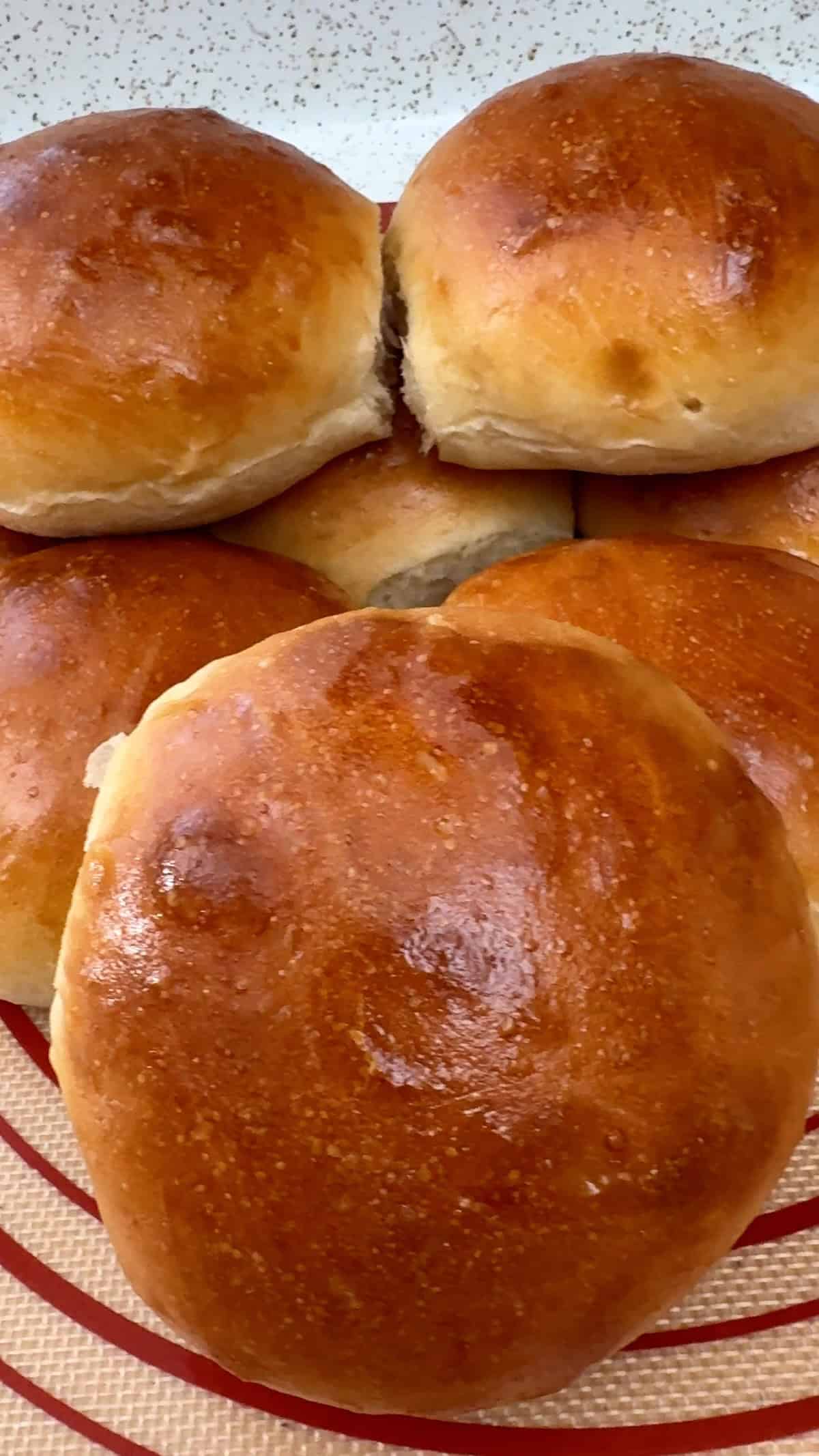 Homemade sandwich rolls stacked on a baking mat