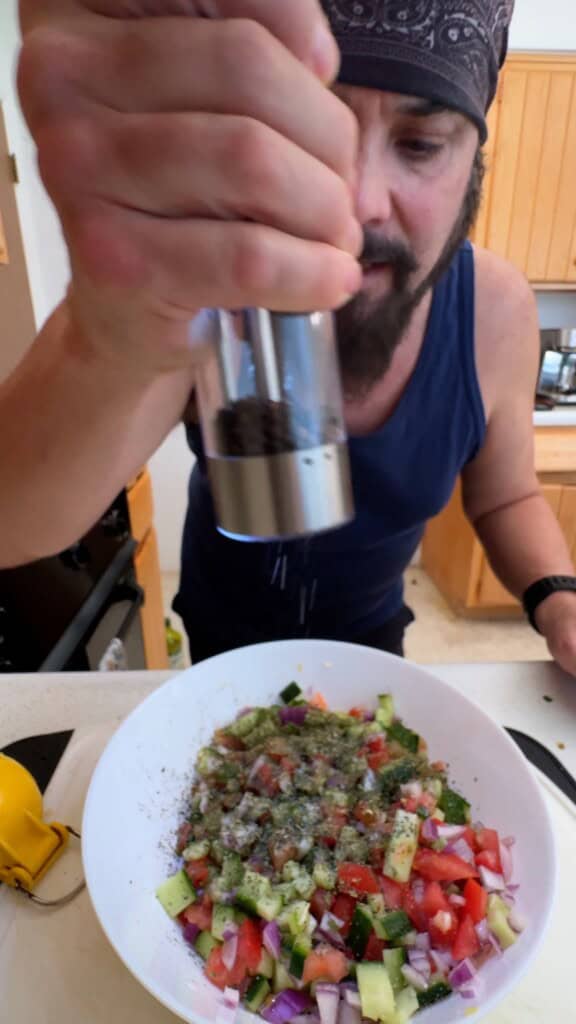 Adding freshly ground black pepper to Shirazi salad