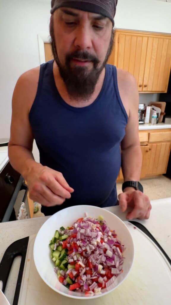 Diced cucumbers, tomatoes, and red onion combined in a bowl before adding the dressing